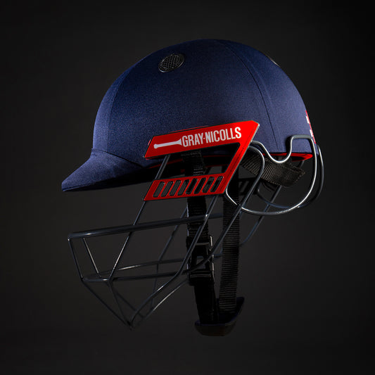 angled view of Gray-Nicolls Atomic 360 Batting Helmet in navy with red grille on dark background