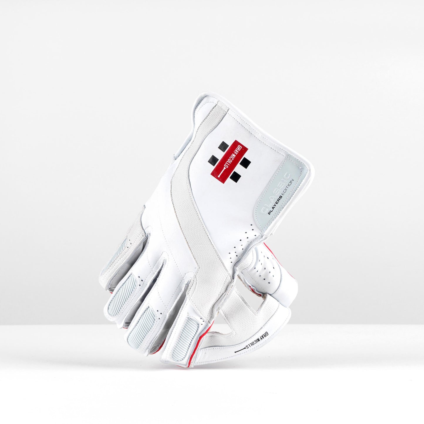 angled side view of Gray-Nicolls white wicket gloves with red logo