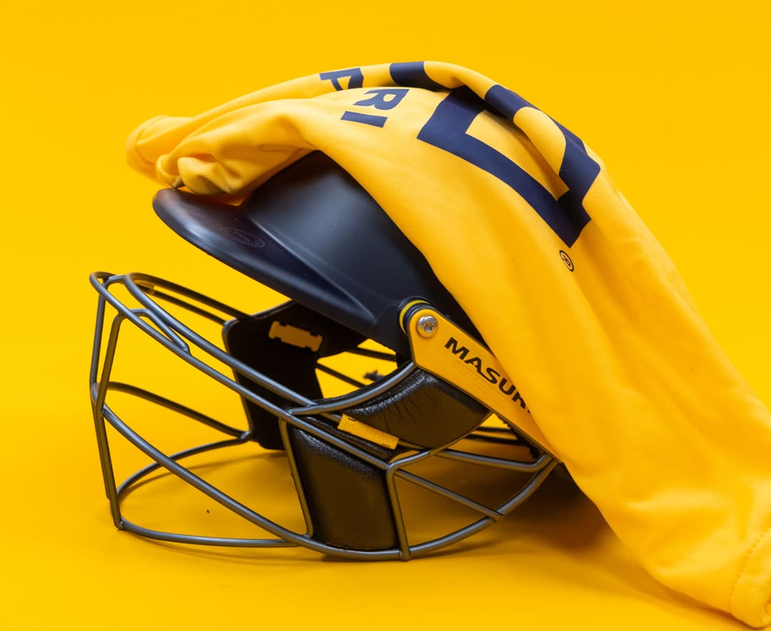 Side view of Masuri E-Line Plus Titanium senior helmet in navy, partially covered by yellow helmet cloth