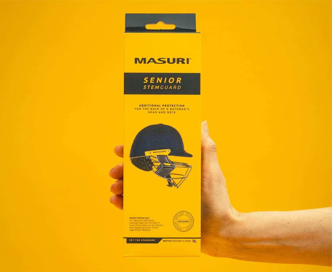 Masuri StemGuard Elite Senior in retail packaging, held in hand against yellow background