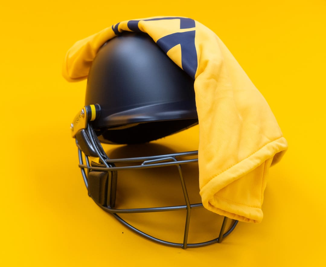 Masuri T-Line Plus Steel junior cricket helmet in navy with yellow bag draped over the grille