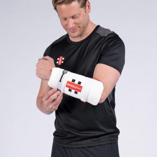 Cricketer fitting the Gray-Nicolls Test Armguard before play