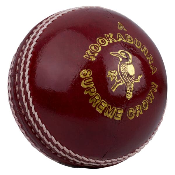 Detailed view of the “Supreme Crown” gold stamp and kookaburra bird emblem on the red leather cricket ball with raised white seam.