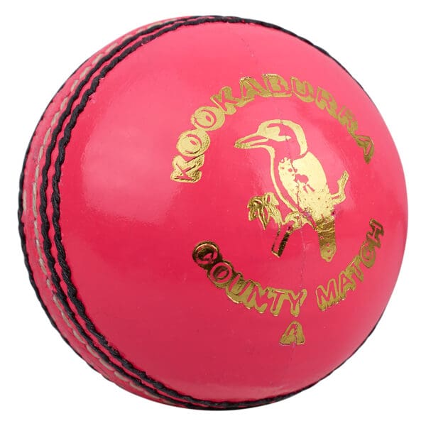 Close-up view of the Kookaburra County Match Cricket Ball in pink, showcasing the gold Kookaburra logo and "County Match" branding with prominent black stitched seam.