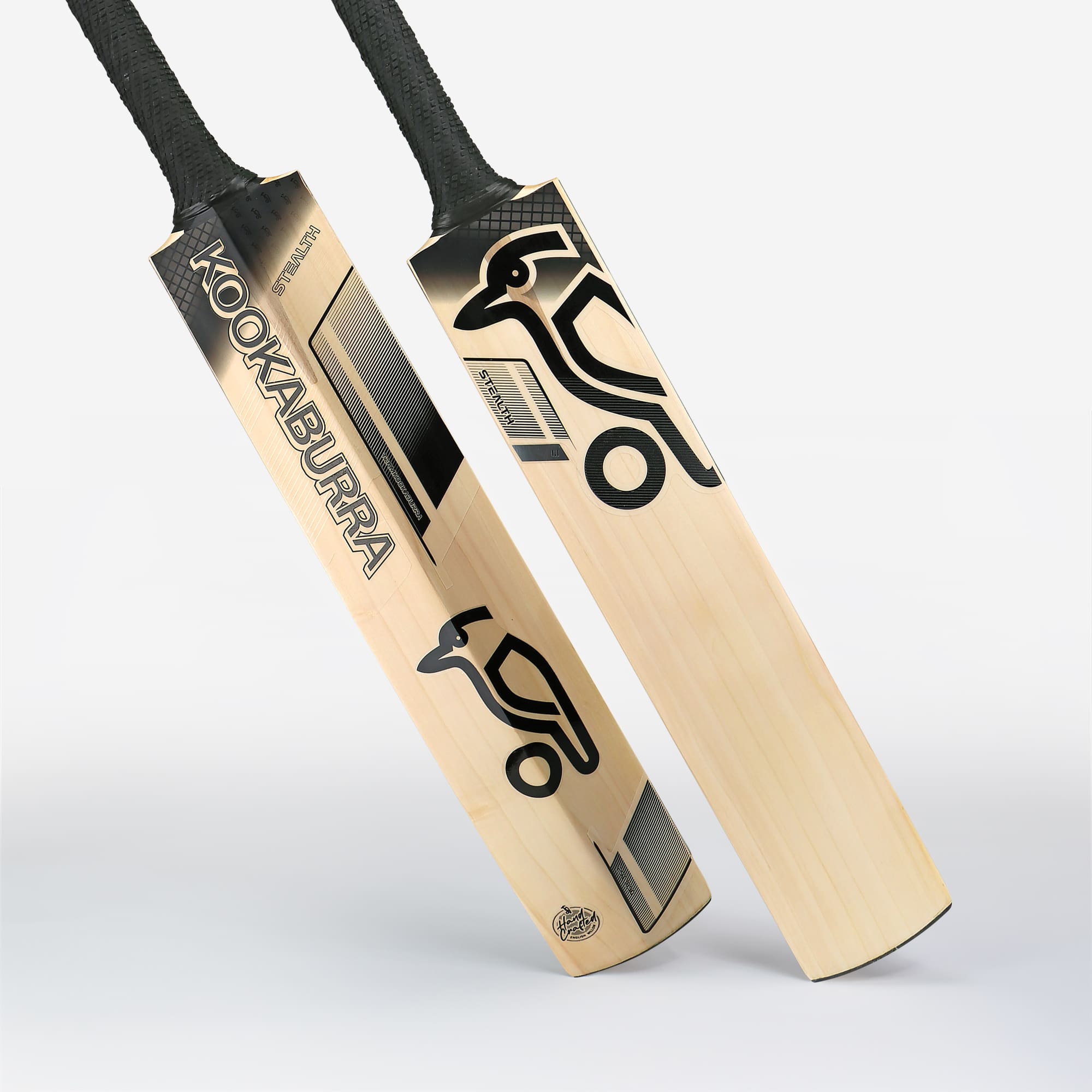 Flat lay close-up of two Kookaburra Stealth 1.1 bats side-by-side, showing face and back detailing with black handle grips.
