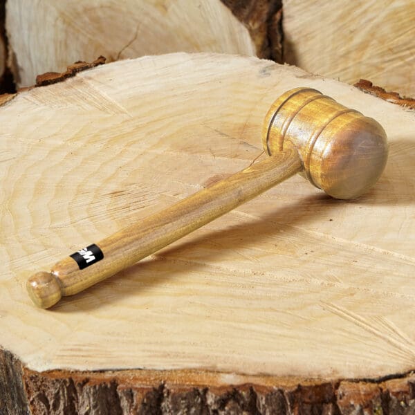 GM cricket bat mallet in centre frame pictured on top of a tree trunk